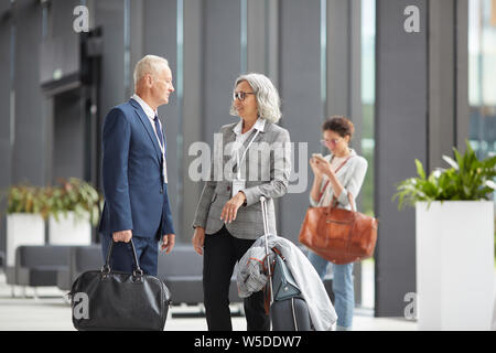 Sorridente multi-etnico business forum partecipanti convenzionale sale riunioni in aeroporto e discutendo le mete di viaggio Foto Stock