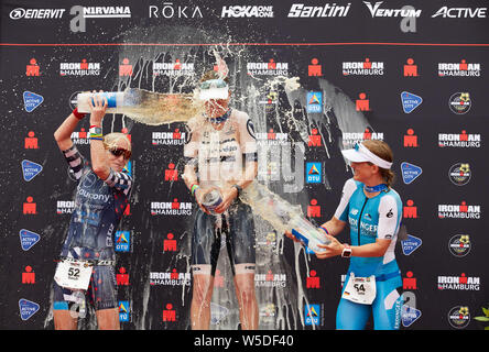 Amburgo, Germania. 28 Luglio, 2019. Triathlon Ironman: World Series/Campionato Tedesco, donne: Sarah Piampiano (l-r) DAGLI STATI UNITI D'AMERICA (2° posto), Susie Cheetham dalla Gran Bretagna (1° posto) e Julia Gajer da Süßen (Germania, terzo posto e miglior tedesco) sono sul podio e bere birra. Credito: Georg Wendt/dpa/Alamy Live News Credito: dpa picture alliance/Alamy Live News Foto Stock