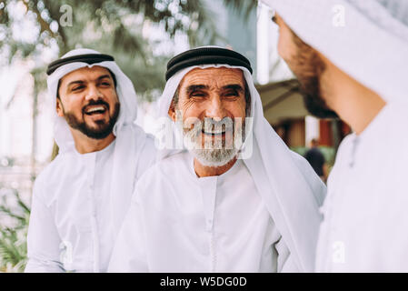 Tre uomini di affari a piedi in Dubai indossando il tradizionale abbigliamento emirati Foto Stock