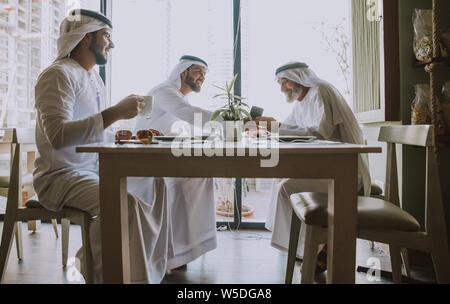 Tre uomini di affari avente un tè in Dubai indossando il tradizionale abbigliamento emirati Foto Stock
