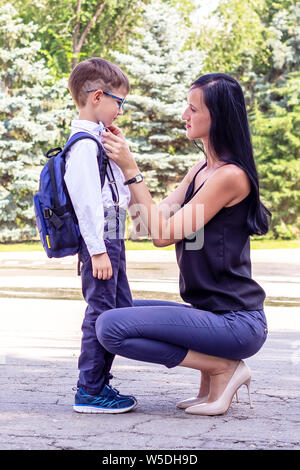 Bruna giovane mamma accompagnatrici il suo primo-livellatrice figlio a scuola. Si torna a scuola Foto Stock