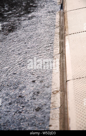 Close-up di una grondaia di strada di città durante la pioggia torrenziale Foto Stock