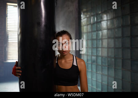 Candide vita ritratto di tenace combattente donna posa con sacco da boxe Boxing in pratica, spazio di copia Foto Stock