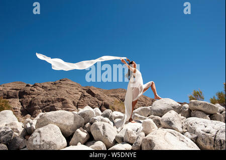 Bella asiatica spirituale Korean American donna che indossa bianco con la sua sciarpa soffiando nel vento del deserto. Foto Stock