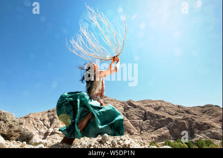 Bella asiatica spirituale Korean American woman dancing in cielo natura potentemente con un grande tumbleweed indigeni scheletro di piante vicine montagne. Foto Stock