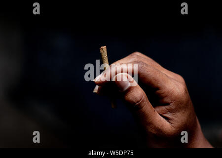 Il beedi è un sottile sigaretta indiano riempito con scaglie di tabacco e avvolto in una Bauhinia racemosa foglia e legato con una stringa in corrispondenza di una estremità. Foto Stock