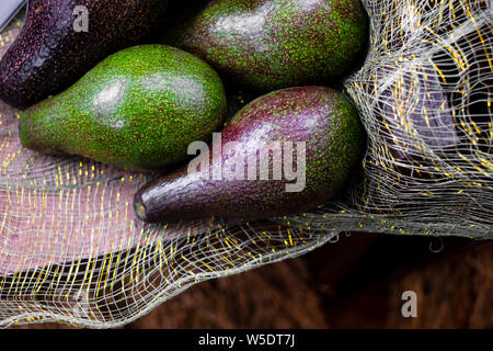 Appena raccolti organici frutti di avocado (AKA burro frutta o alligator pear) sul tessuto a rete. Esso contiene quantità sostanziali di acidi grassi sani. Foto Stock