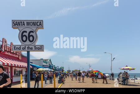 Los Angeles California USA. Maggio 30, 2019. Santa Monica Pier e Route 66 Fine del sentiero, colore bianco segno. La gente camminare al molo, cielo blu backgro Foto Stock