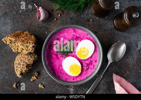 Fredda zuppa di barbabietole con uova sode o in una ciotola su sfondo scuro. Tabella Vista dall'alto. Cibo sano, la perdita di peso concept Foto Stock