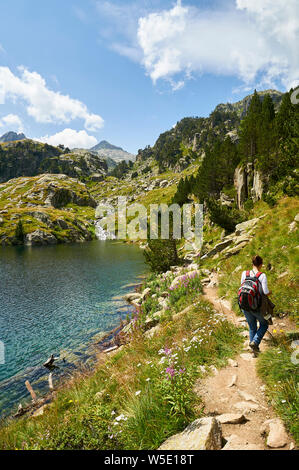 Escursionista femminile accanto a Estanh Major de Colomèrs a Aigüestortes i Estany de Sant Maurici National Park (Valle de Arán, Lleida, Pirenei, Catalogna, Spagna) Foto Stock