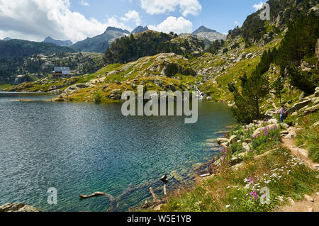 Escursionista femminile accanto a Estanh Major de Colomèrs a Aigüestortes i Estany de Sant Maurici National Park (Valle de Arán, Lleida, Pirenei, Catalogna, Spagna) Foto Stock