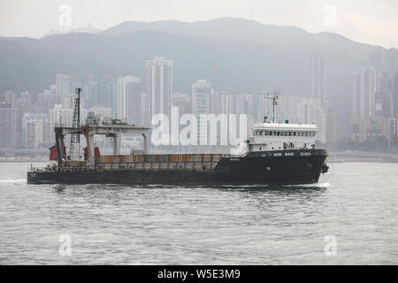 Contenitore nave Nim Wan in Victoria Harbour, Isola di Hong Kong grattacieli sullo sfondo Foto Stock