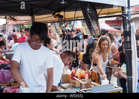 Preparare i fornitori corndogs Coreano come un cliente raggiunge per i condimenti a Ottawa Asian Fest il Mercato Notturno, 2019. Ottawa, Ontario, Canada. Foto Stock