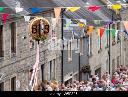 Langholm, Dumfries and Galloway, Scotland, Regno Unito. Il 26 luglio 2019. L'Orzo Bannock è tenuto aloft durante la camminata fino la Kirk Wynd. Foto Stock
