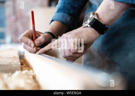 Carpenter lavorando su macchine per la lavorazione del legno in falegnameria shop. Un uomo che lavora in un negozio di falegnameria. Foto Stock