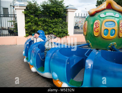 Russia, Arkhangelsk - Luglio 2019. Due tre-anno-vecchio ragazzo bianco ride in bambini open-giostra treno. Un bambino piange. Divertimento, attività, impressione Foto Stock