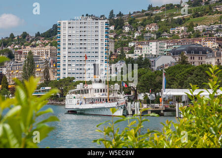 Belle Epoque vintage restaurati in barca a remi denominata Italie ormeggiata presso il molo a Montreux sul Lago di Ginevra (Lac Leman), Vaud, Svizzera con Eurotel edificio Foto Stock