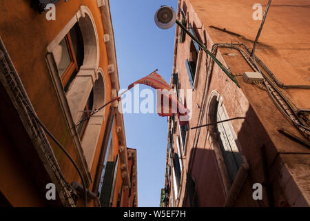 Guardando verso l'alto una bandiera di Venezia su edifici veneziani in estate Foto Stock