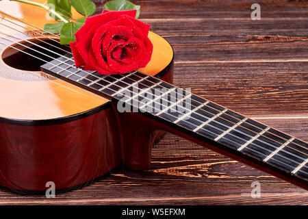 Rosa rossa sulla chitarra acustica. Foto Stock