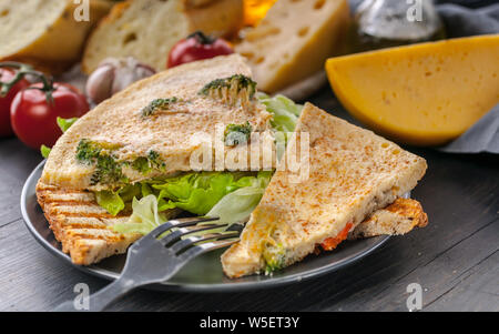 Una gustosa prima colazione. Frittata. Frittata con verdure e formaggio su pane tostato con insalata di ghiaccio. In primo piano Foto Stock