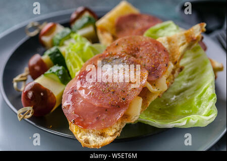 Carne di manzo affumicato con spezie su pane tostato con insalata e tartine. Close-up Foto Stock