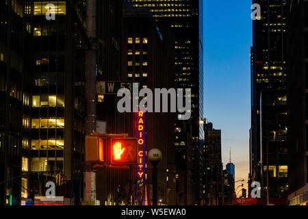 New York, New York, Stati Uniti d'America - Novembre 2018: semaforo rosso e Radio City Music Hall di Manhattan di notte. Persone e di traffico può essere visto intorno a questa IC Foto Stock