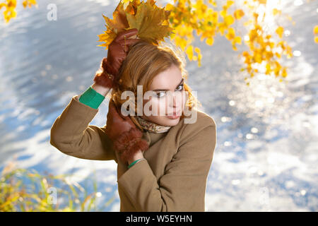 Giovane donna nel parco e trattiene il Giallo autunno foglie di acero. Foto Stock