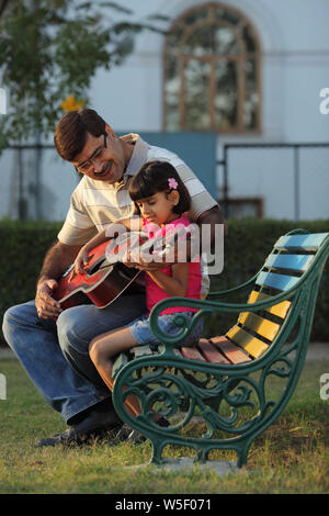 Uomo che assiste sua nipote nel suonare la chitarra Foto Stock