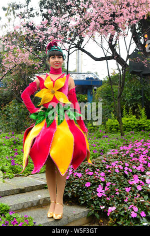 Un animatore vestito con un mantello colorato decorato con fiori pone a Guangzhou Chimelong località turistica della città di Guangzhou, a sud della Cina di Gua Foto Stock