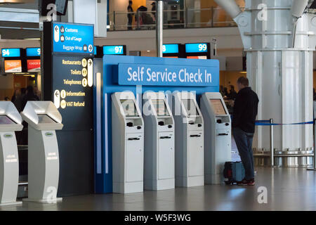 L'uomo, passeggero, persona in piedi presso la compagnia aerea self service fila di morsetti o i computer di controllo prima di salire a bordo di un volo a Cape Town Aeroporto Foto Stock