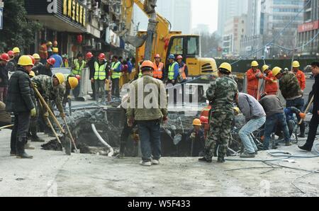 Lavoratori cinesi verificare la continua perdita di tubazioni di acqua causando il crollo della strada su una strada di Hangzhou, a est della Cina di provincia dello Zhejiang, 7 Ma Foto Stock