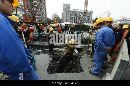 Lavoratori cinesi verificare la continua perdita di tubazioni di acqua causando il crollo della strada su una strada di Hangzhou, a est della Cina di provincia dello Zhejiang, 7 Ma Foto Stock