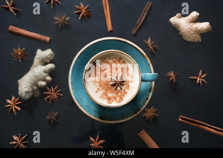 Masala Indian del tè o del caffè in tazza con spezie sul calcestruzzo nero tabella. Vista dall'alto. Foto Stock