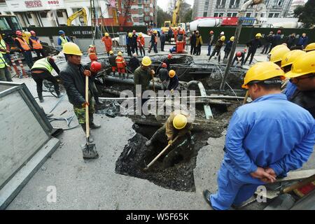 Lavoratori cinesi verificare la continua perdita di tubazioni di acqua causando il crollo della strada su una strada di Hangzhou, a est della Cina di provincia dello Zhejiang, 7 Ma Foto Stock