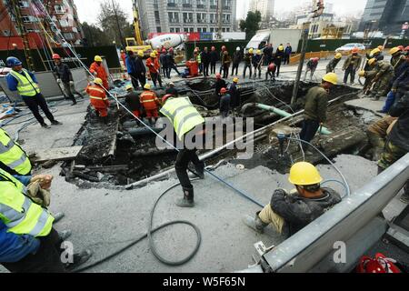 Lavoratori cinesi verificare la continua perdita di tubazioni di acqua causando il crollo della strada su una strada di Hangzhou, a est della Cina di provincia dello Zhejiang, 7 Ma Foto Stock