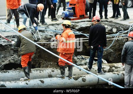 Lavoratori cinesi verificare la continua perdita di tubazioni di acqua causando il crollo della strada su una strada di Hangzhou, a est della Cina di provincia dello Zhejiang, 7 Ma Foto Stock