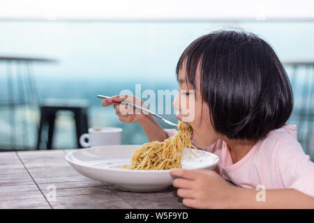 Asian poco ragazza cinese di mangiare spaghetti in outdoor cafe Foto Stock