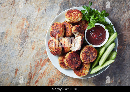 Polacco polpette di carne serviti con fette di cetriolo e salsa barbecue su una piastra bianca su una tavola orizzontale, vista da sopra, laici piatta Foto Stock