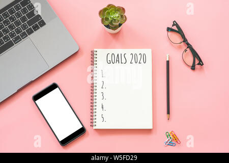 2020 Anno nuovo concetto. Elenco degli obiettivi in cancelleria, notebook, laptop, smartphone, pot impianto su pink color pastello con spazio di copia Foto Stock