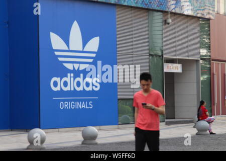 --FILE--un residente locale passeggiate passato un annuncio per Adidas a Chongqing Cina, 28 agosto 2018. Adidas ha aumentato la sua moneta-regolati t annuale Foto Stock