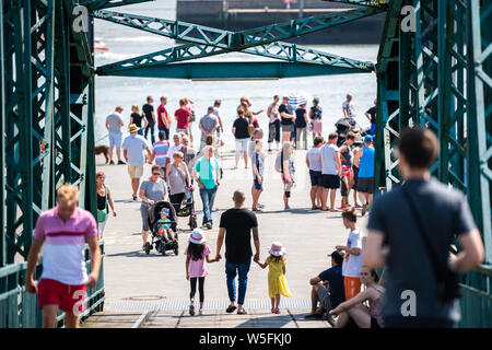 Wilhelmshaven, Germania. 28 Luglio, 2019. Un padre e le sue due figlie attraversare un ponte per le barche DGzRS il giorno del salvataggio in mare dei soccorritori della Deutsche Gesellschaft zur Rettung Schiffbrüchiger. Credito: Mohssen Assanimoghaddam/dpa/Alamy Live News Foto Stock