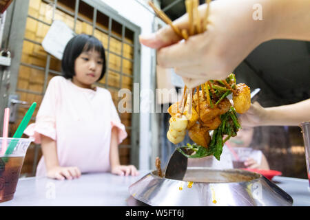 Asian poco ragazza cinese di mangiare hot pot in un ristorante di Melaka Foto Stock