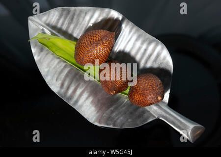 Snakefruit su una forma di foglia argento piastra con sfondo scuro Foto Stock