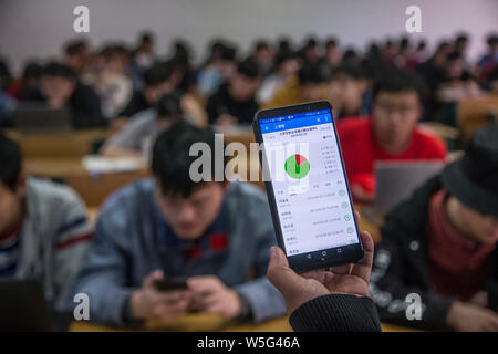 Un insegnante utilizza l'App che consente il tracciamento delle presenze degli studenti sul suo smartphone in una classe a Hangzhou dianzi University di Hangzhou, Oriente Cina Foto Stock