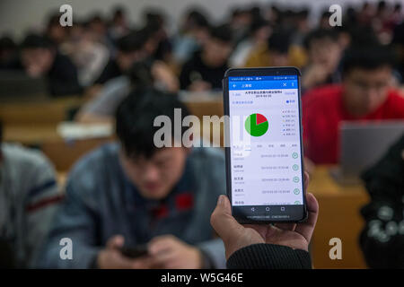 Un insegnante utilizza l'App che consente il tracciamento delle presenze degli studenti sul suo smartphone in una classe a Hangzhou dianzi University di Hangzhou, Oriente Cina Foto Stock