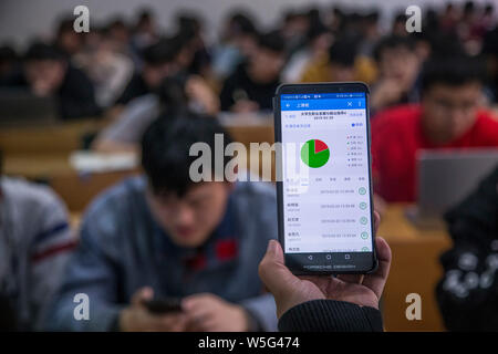 Un insegnante utilizza l'App che consente il tracciamento delle presenze degli studenti sul suo smartphone in una classe a Hangzhou dianzi University di Hangzhou, Oriente Cina Foto Stock