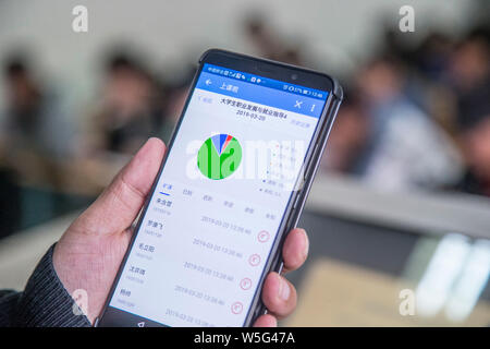 Un insegnante utilizza l'App che consente il tracciamento delle presenze degli studenti sul suo smartphone in una classe a Hangzhou dianzi University di Hangzhou, Oriente Cina Foto Stock