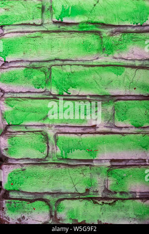 Dipinto di verde il vecchio muro di mattoni con base bianca, semplice graffiti, sfondo o texture con ruvida cercando lavoro di vernice Foto Stock