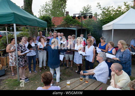 Coro locale cantare; un gruppo di persone in un coro che canta al di fuori in un pub che cantano, Burrough Green Village, Cambridgeshire Regno Unito Foto Stock