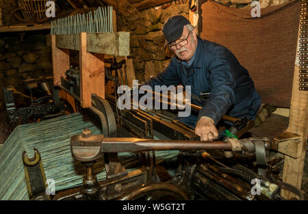 Gearrannan, Shottland- Giugno 26, 2018: l uomo è la tessitura Harris Tweed su un antico telaio di tessitura nella Gearrannan Blackhouse village Foto Stock